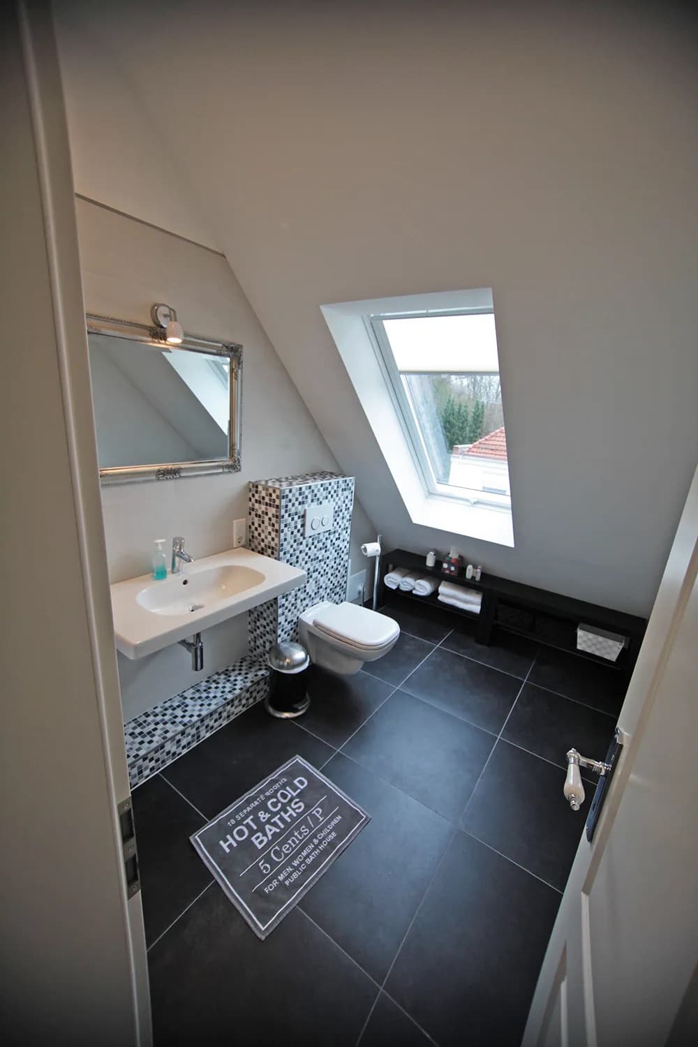 Bad der Atelier-Wohnung der Villa Emmilio mit WC und dunklem Boden, möblierte Ferienwohnung in Bad Oeynhausen.