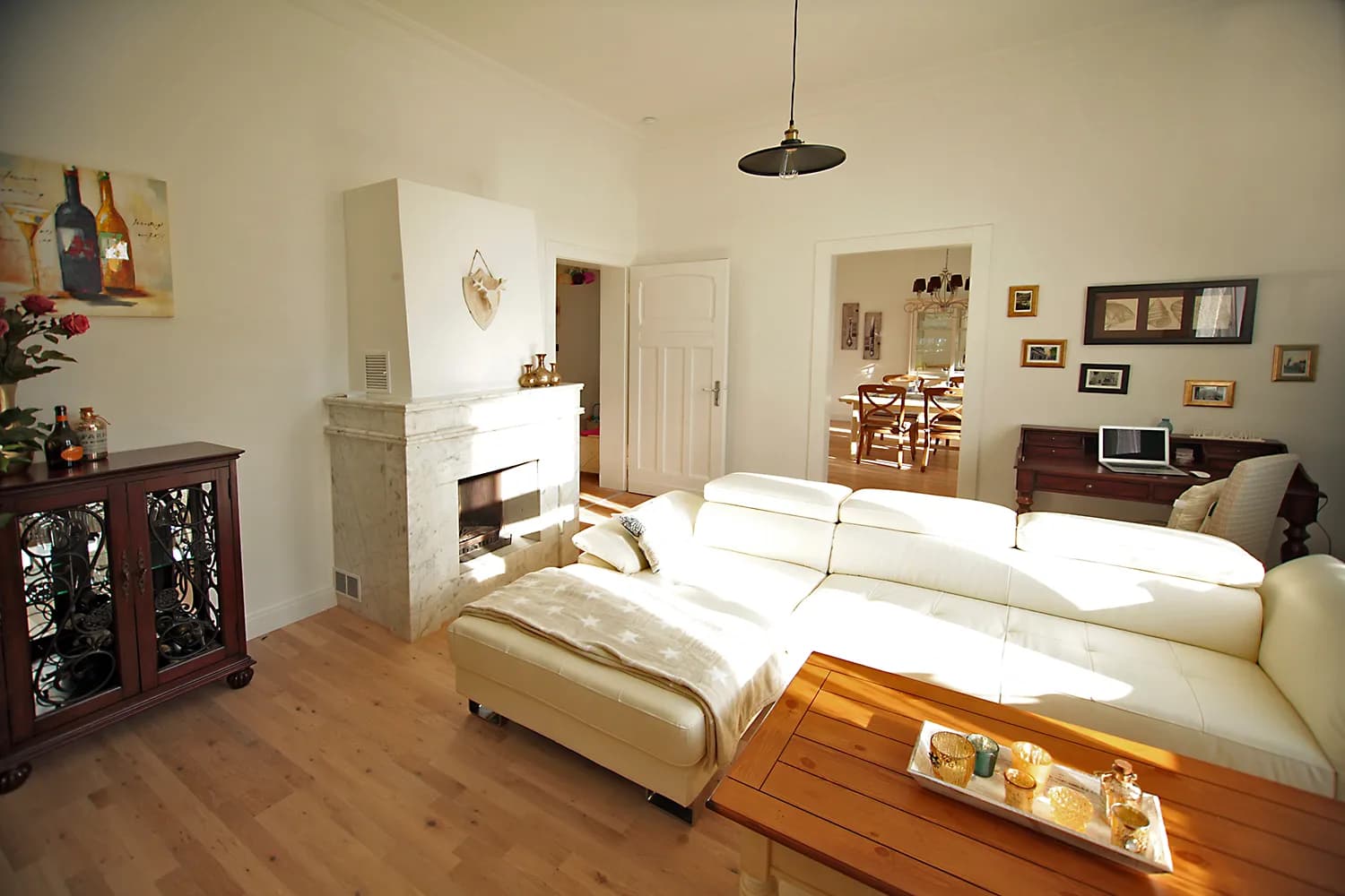Wohnzimmer der Bel-Étage-Wohnung der Villa Emmilio mit Ledersofa und Marmorkamin, nahe dem Herzzentrum in Bad Oeynhausen.