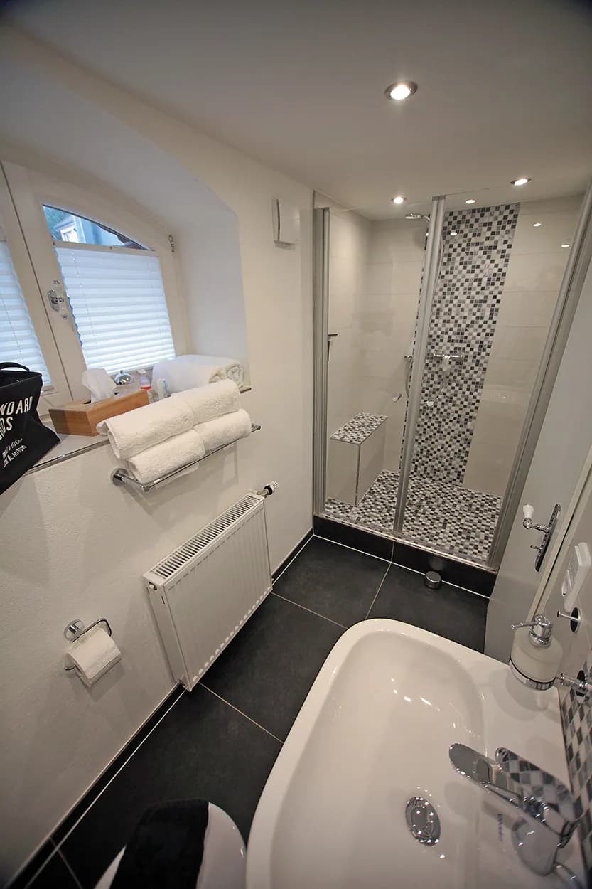 Bad der Souterrain-Wohnung der Villa Emmilio mit Dusche, Badewanne und Handtüchern, möbliertes Apartment in Bad Oeynhausen.