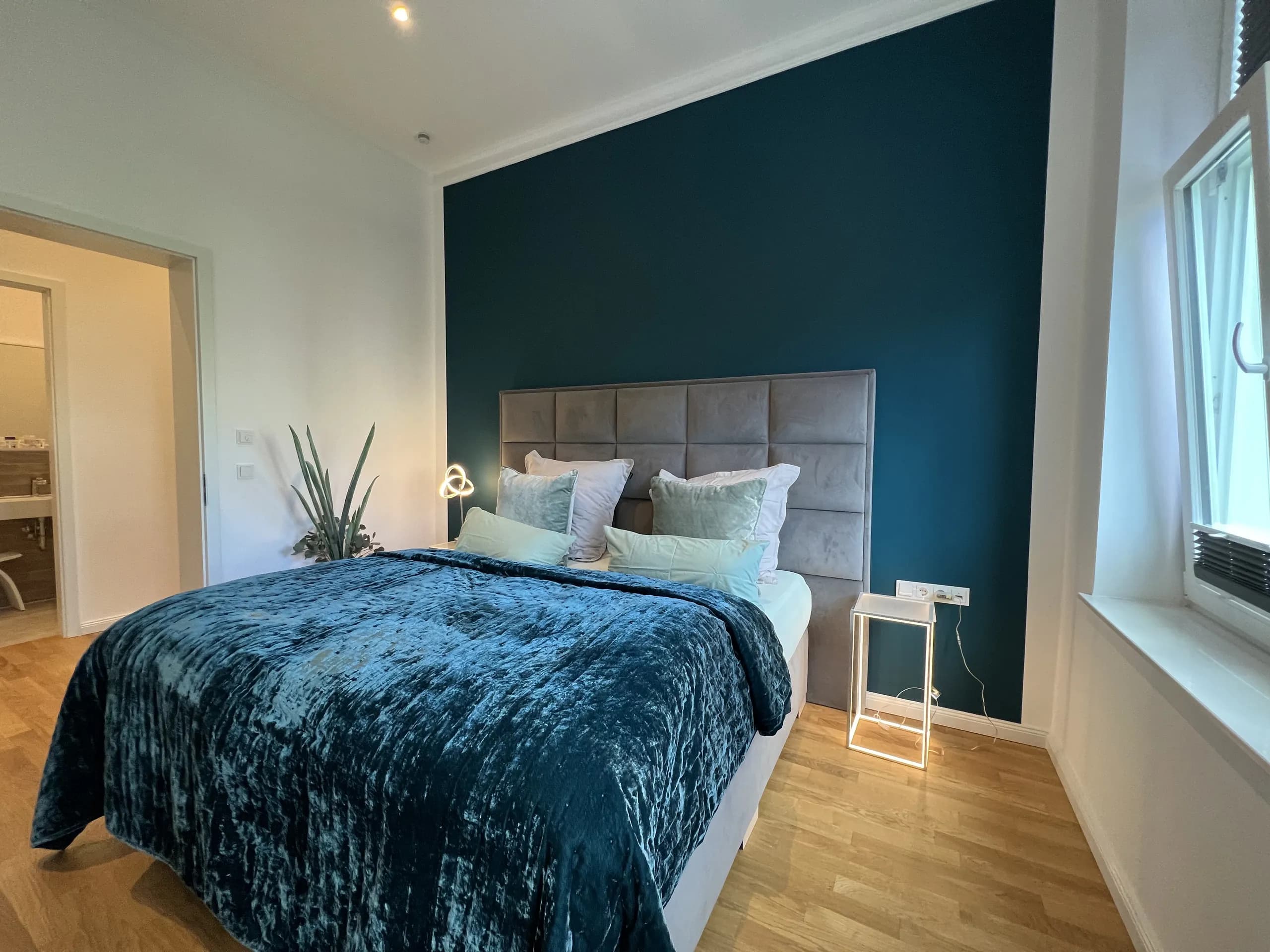 Schlafzimmer der Villa Maria mit Petrolwand und Rundbogenfenstern, Wohnen auf Zeit in Bad Oeynhausen.