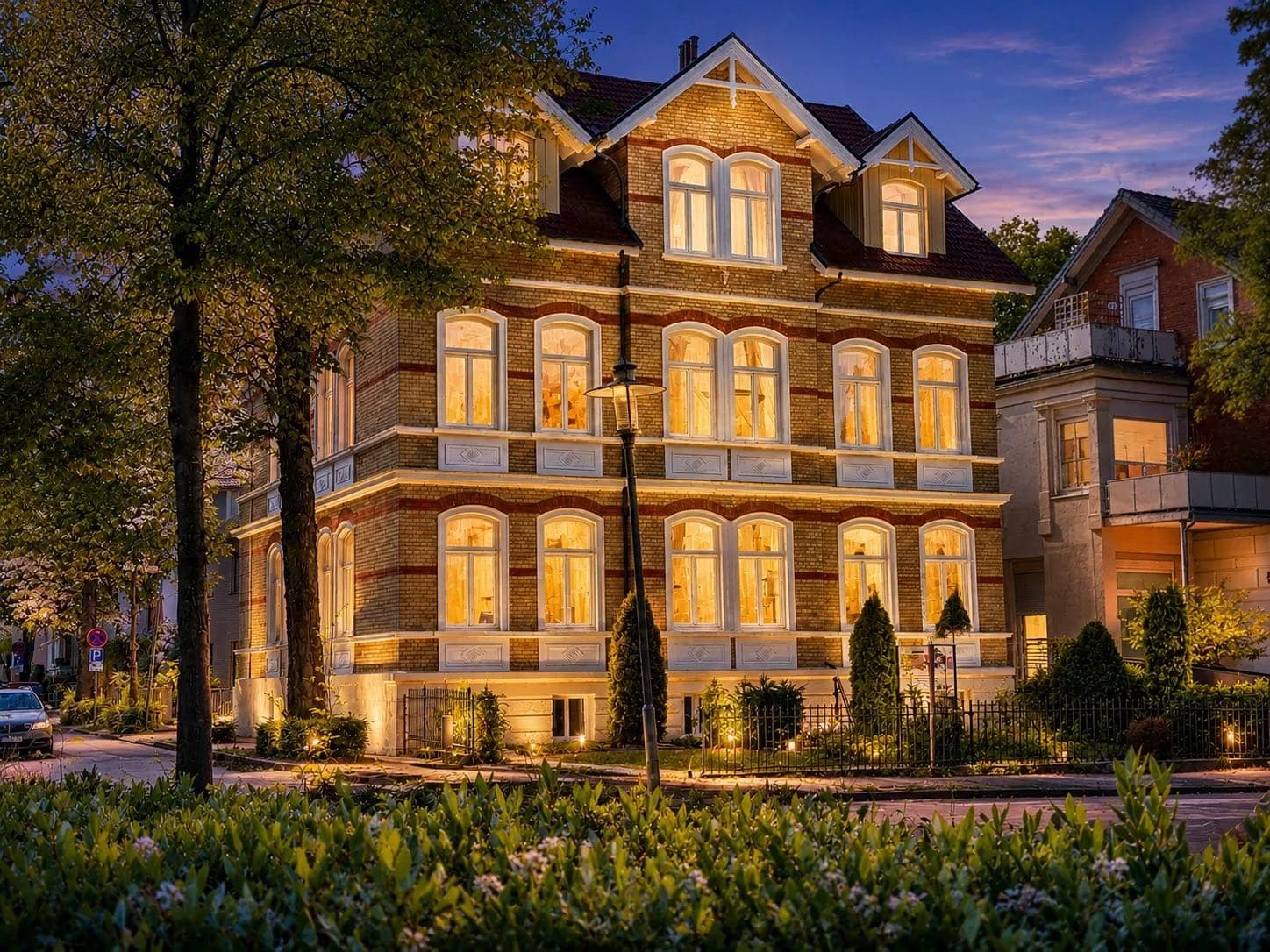 Denkmalgeschütztes VIOS Townhouse zur blauen Stunde hinter Hecken, Boardinghaus am Kurpark in Bad Oeynhausen.