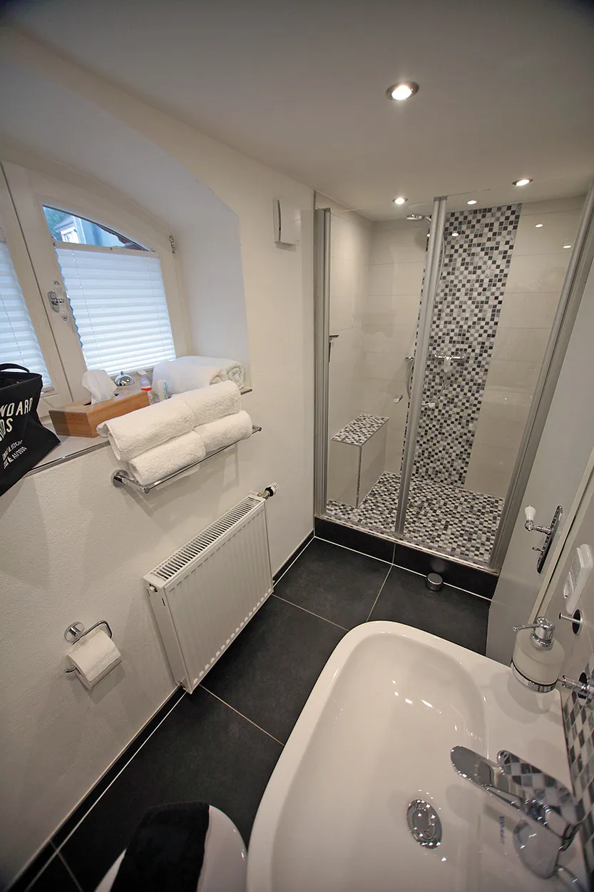 Bad der Souterrain-Wohnung der Villa Emmilio mit Dusche, Badewanne und Handtüchern, möbliertes Apartment in Bad Oeynhausen.