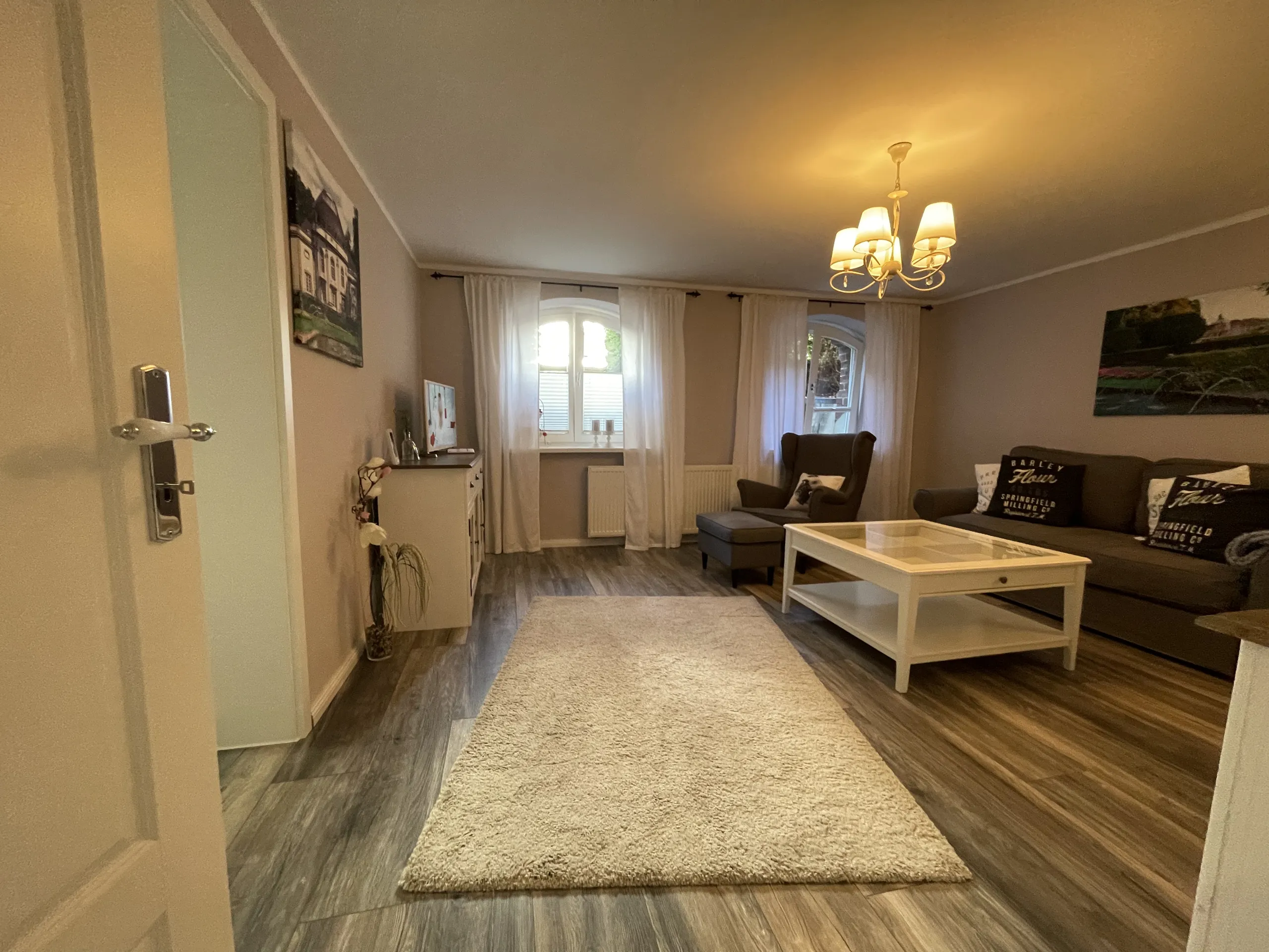 Wohnbereich der Souterrain-Wohnung der Villa Emmilio mit beigem Sofa, möbliertes Apartment in Bad Oeynhausen.