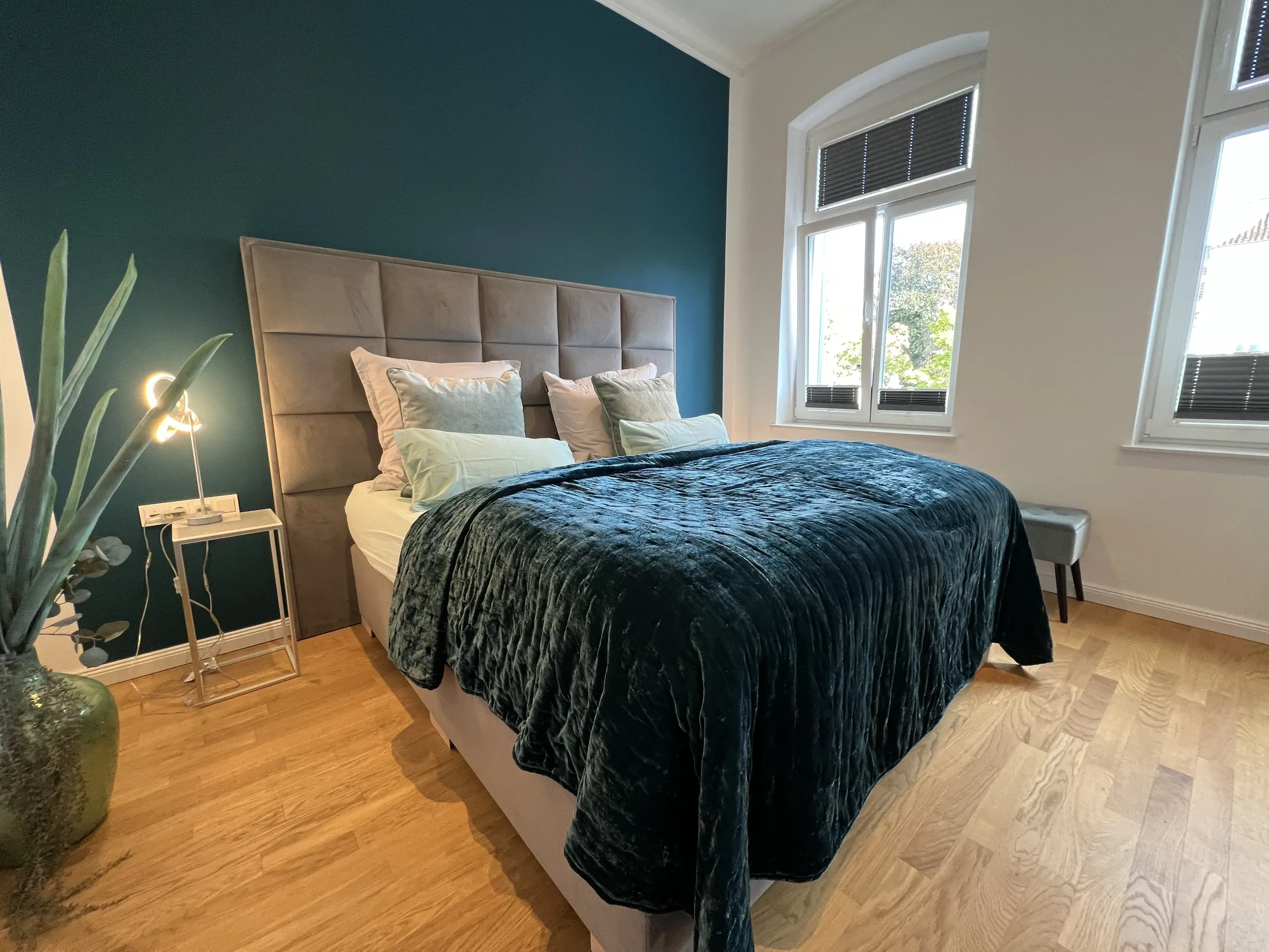 Schlafzimmer der Villa Maria Bel Étage mit petrolfarbener Wand und Doppelbett, möblierte Ferienwohnung in Bad Oeynhausen.