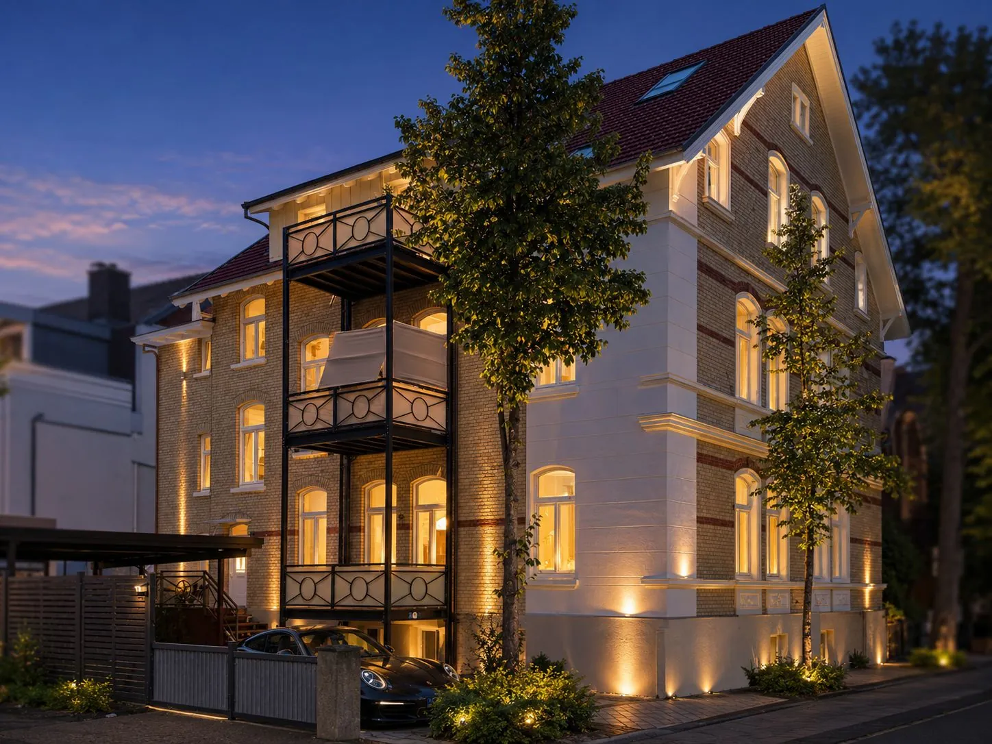 VIOS Townhouse bei Dämmerung mit schmiedeeisernen Balkonen und Klinkerfassade, möbliertes Apartment in Bad Oeynhausen.